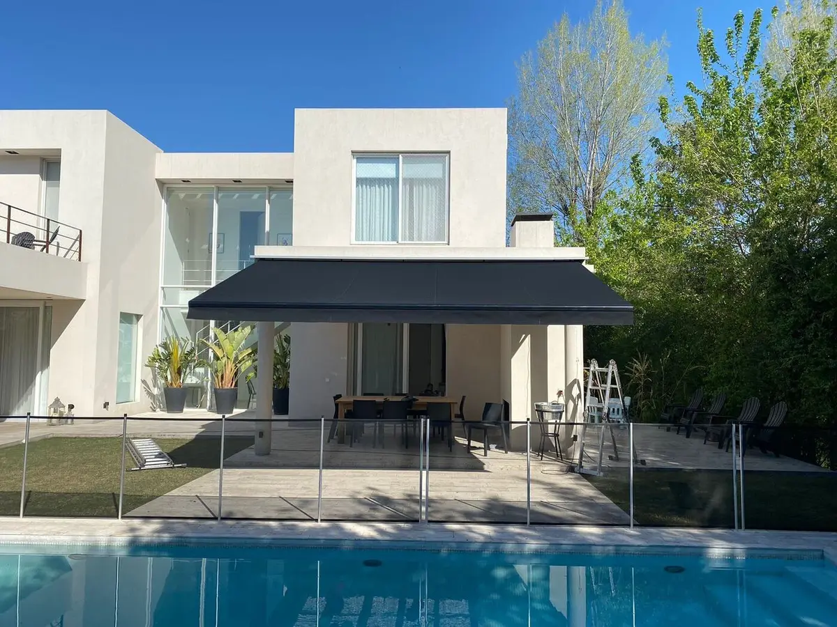 Toldo retráctil de cofre sobre la galería de una casa con pileta